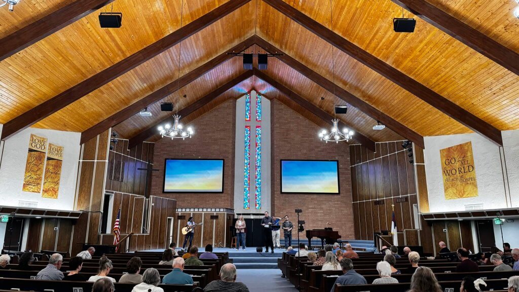 Interior, large sanctuary with two Martin Audio SXC115 cardioid subwoofers and four Martin Audio CDD12 speakers hanging from A-frame ceiling; this church sound system upgrade produced better church sound