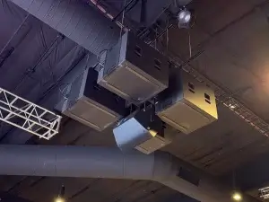 Contemporary church sanctuary, interior, upward view of four subwoofers and a front fill speaker hanging securely from a dark ceiling with church audio visual equipment (such as truss) and ductwork in the background