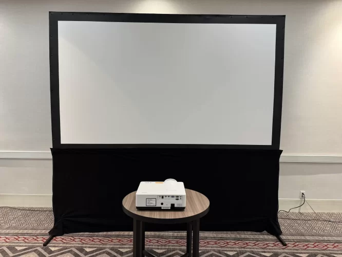 Professional mobile projector screen setup in corporate conference room with NEC short-throw projector on round table, demonstrating clean installation process
