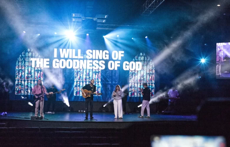 Modern sanctuary, interior, worship band backed by vibrant LED church stage lighting with fog and a large LED video wall